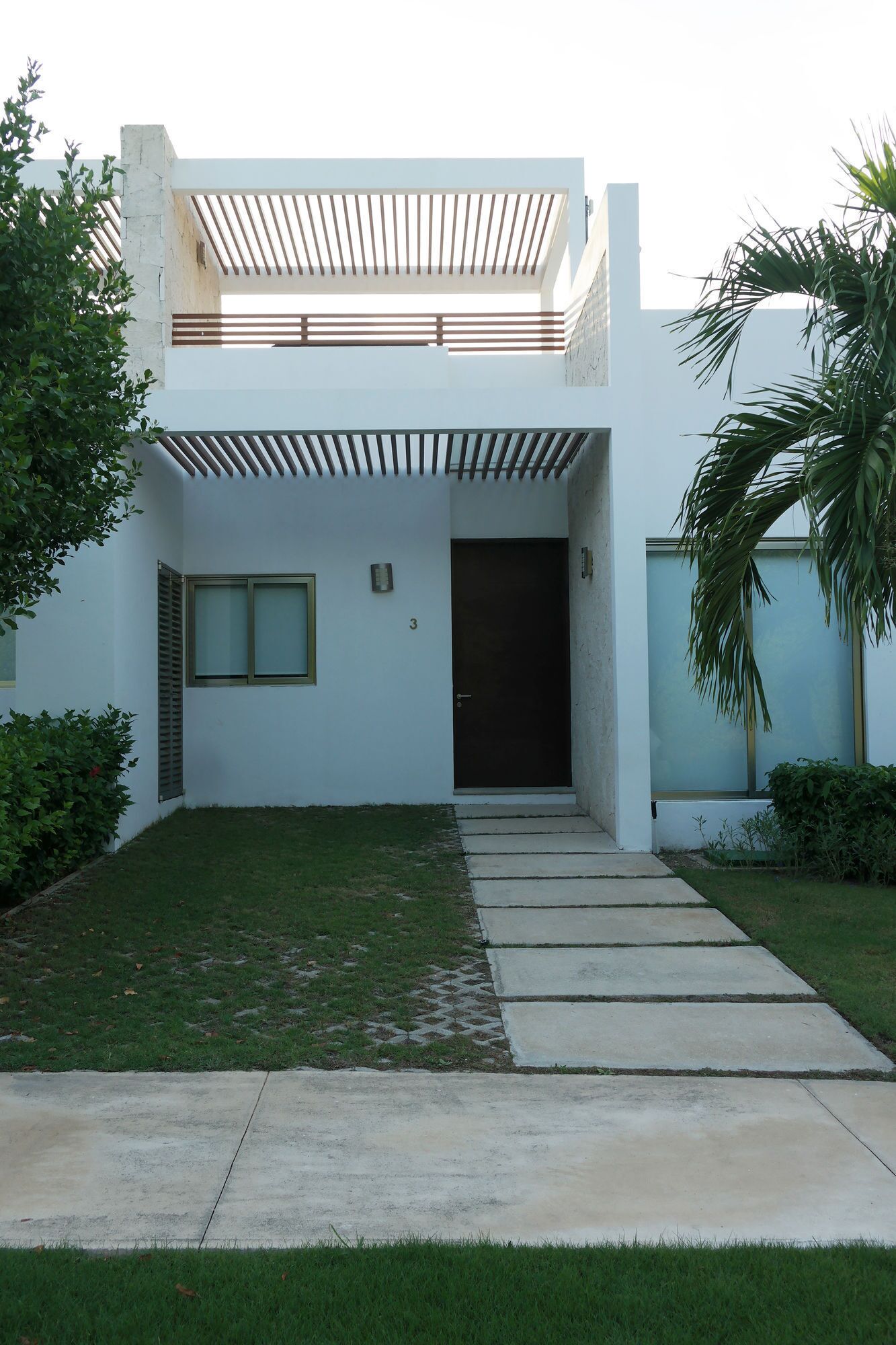 Una casa moderna a due piani con tetto piatto, veranda coperta e porta d'ingresso.