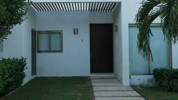 Una casa moderna a due piani con tetto piatto, veranda coperta e porta d'ingresso.