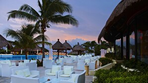 A resort with outdoor seating, palm trees, and a pool.
