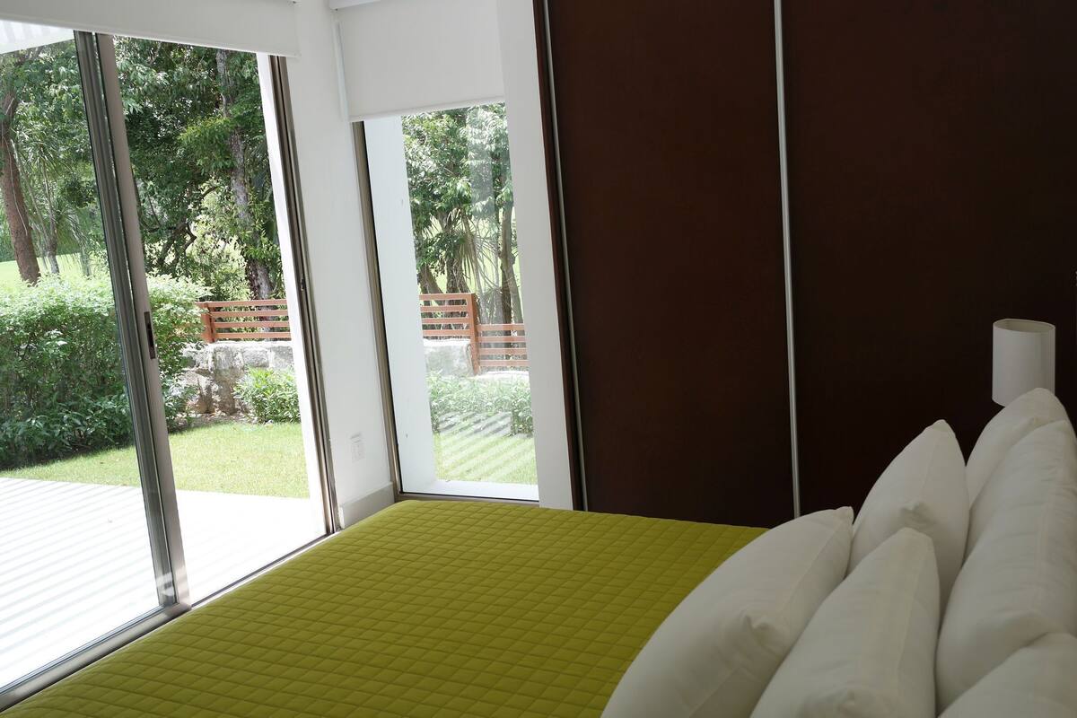 Une chambre à coucher avec un lit, une fenêtre et une vue sur un jardin.