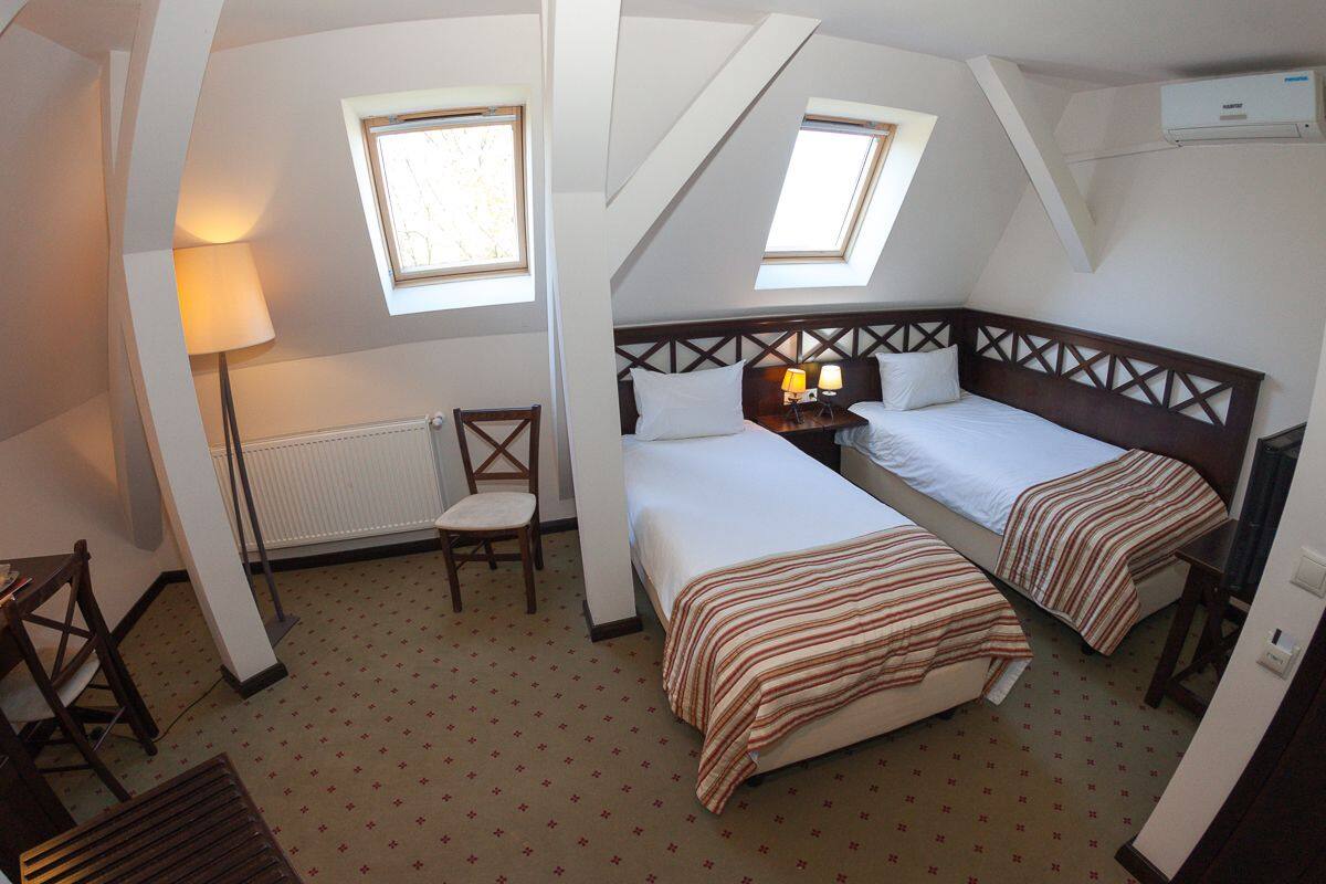 A room with two beds, a chair, a table, and a radiator.