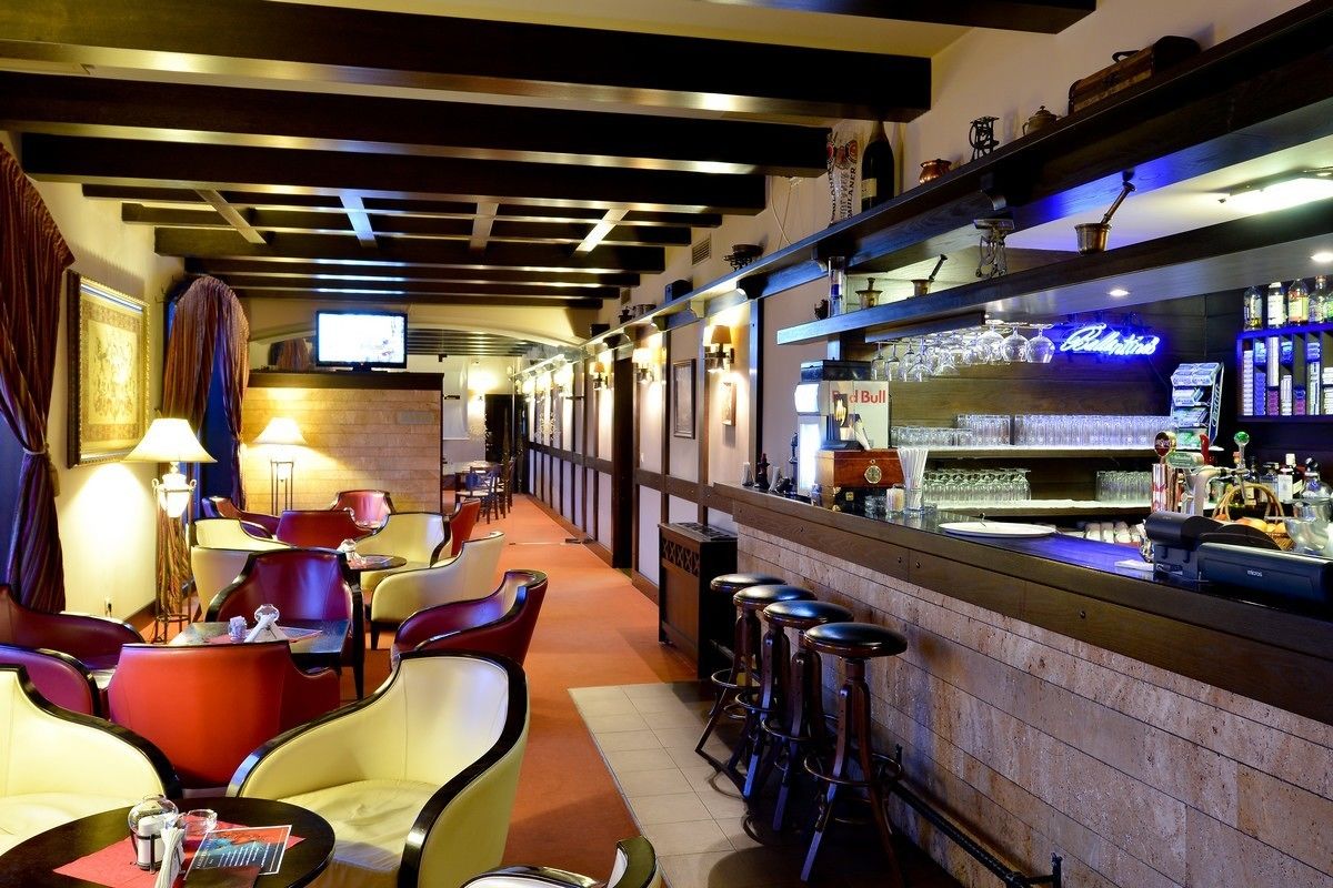 Eine Bar mit Hockern, einer Theke mit einem Neonzeichen und einem an der Wand befestigten Fernseher.