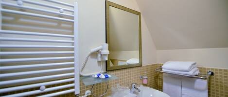 Une salle de bain avec un lavabo blanc, un miroir, un porte-serviettes et un distributeur de serviettes.
