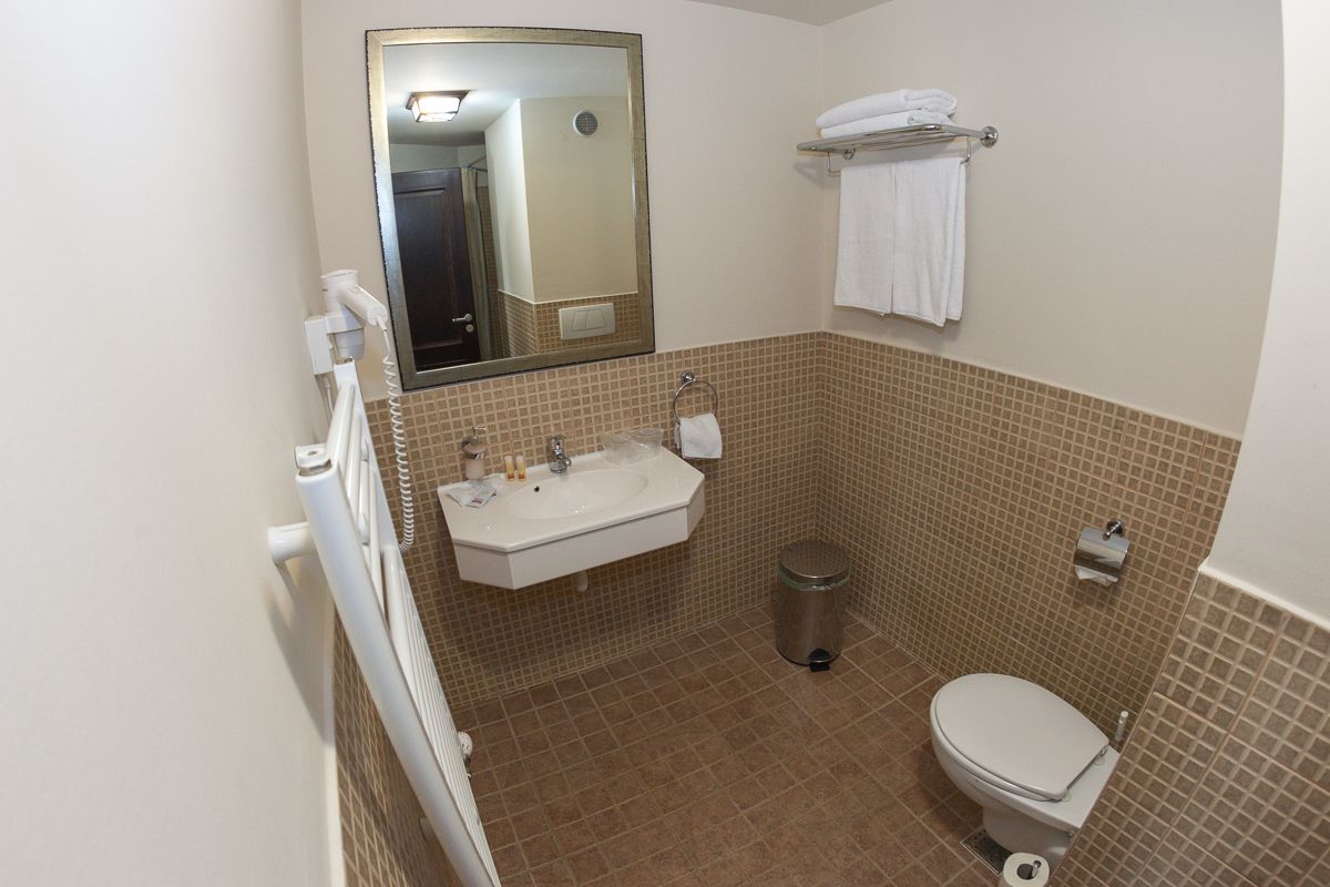 A bathroom with a sink, mirror, toilet, and towel rack.