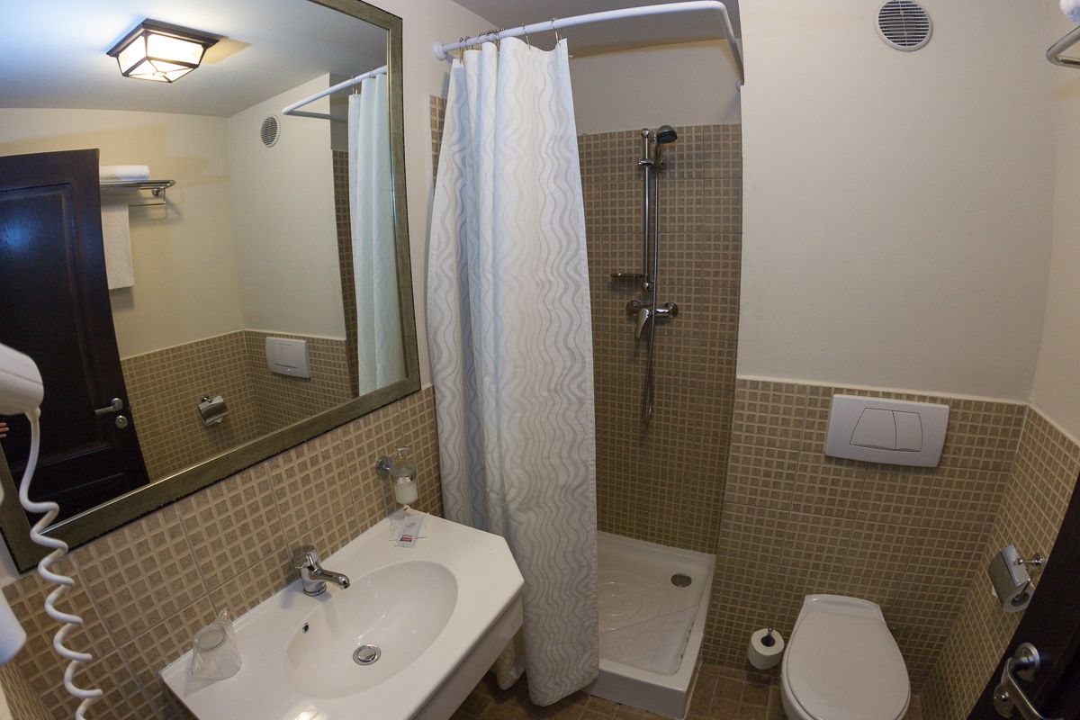 A bathroom with a sink, toilet, shower, and a towel rack.
