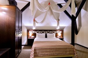 Habitación de hotel con cama, mesita de noche, armario y dosel.