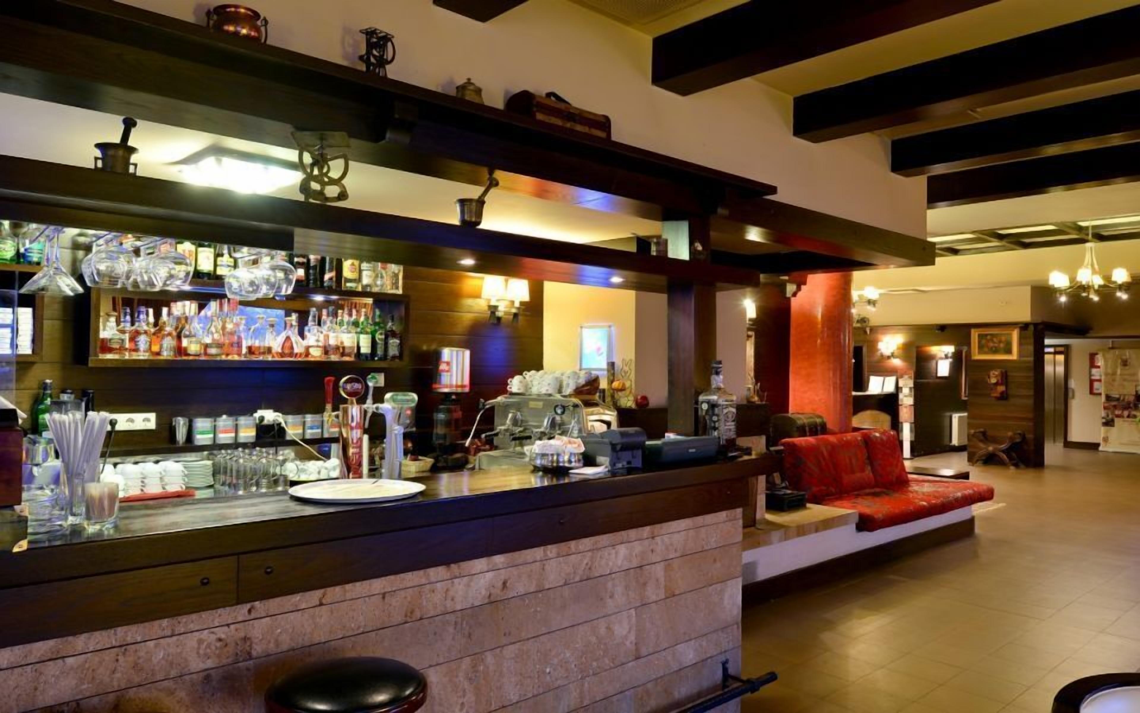 Een bar met een toog, krukken en een zithoek met een rode bank.