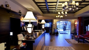 A reception area with a desk, chairs, and a reception desk with a sign. There is a large rug on the floor and a chandelier hanging from the ceiling. - Hotel Gradina Morii (Sighetu Marmatiei)