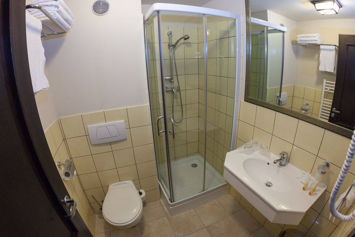 A bathroom with a glass-enclosed shower, a sink, and a toilet.