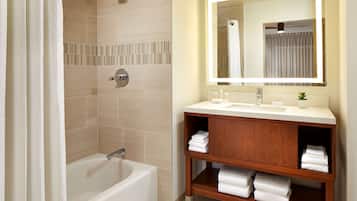 A modern bathroom with a bathtub, a vanity with a mirror, and neatly folded towels.
