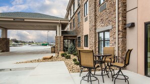 A building with a covered outdoor seating area, stone facade, and a clear sky. - Sleep Inn & Suites Dayton South (Dayton)