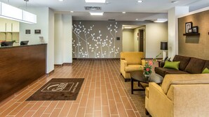A hotel lobby with a reception desk, seating area, and a decorative wall. - Sleep Inn & Suites Dayton South (Dayton)