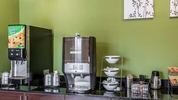 Una estación de café con dos máquinas de café, un dispensador de bebidas y una exhibición de granos de café.