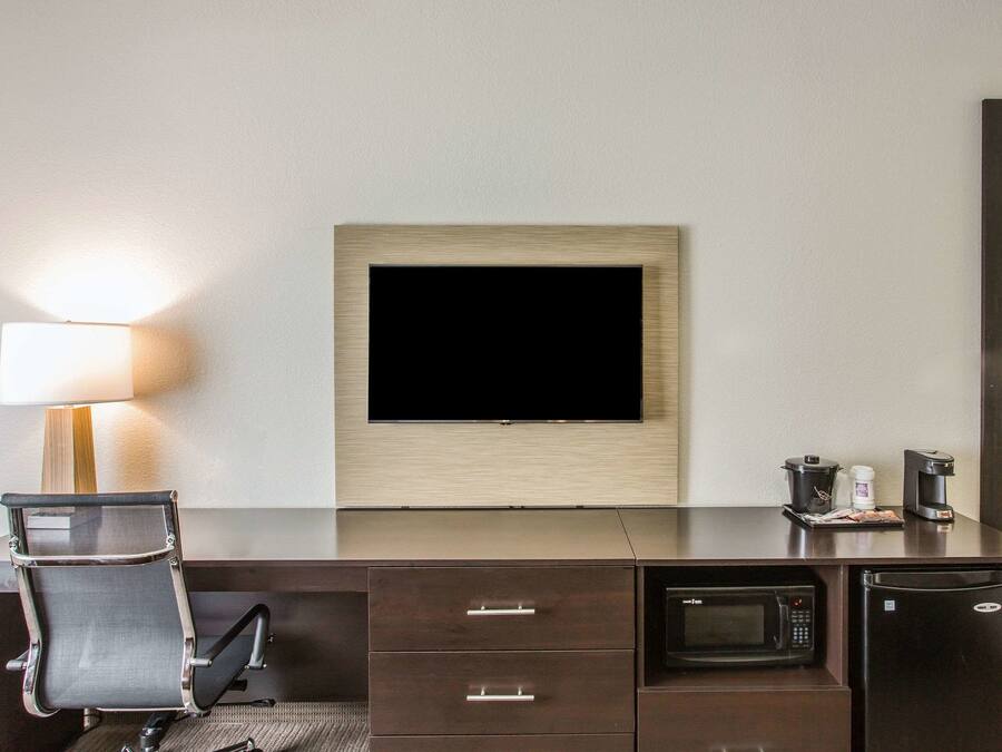 Habitación de hotel con escritorio, televisión, lámpara, microondas y refrigerador.