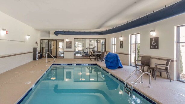 An indoor swimming pool with a covered seating area and a pool lift sign. - Sleep Inn & Suites Dayton South (Dayton)