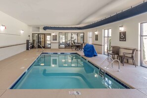 An indoor swimming pool with a covered seating area and a pool lift sign.