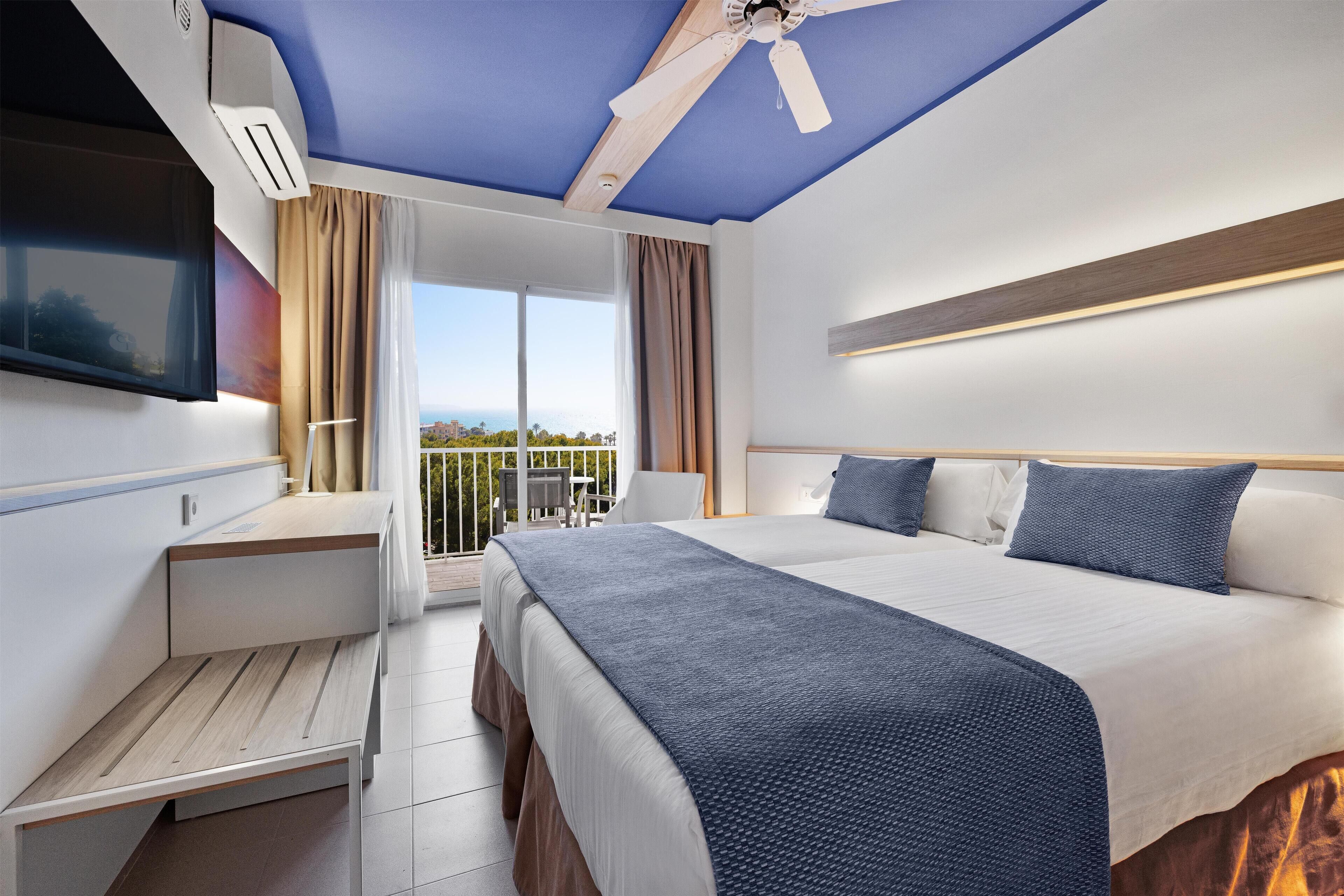 Ein modernes Hotelzimmer mit einem großen Bett, einem Schreibtisch und einem Balkon mit Blick.