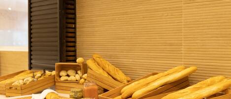 A display of bread and pastries in wooden crates, a wicker basket, and a jar of jam.