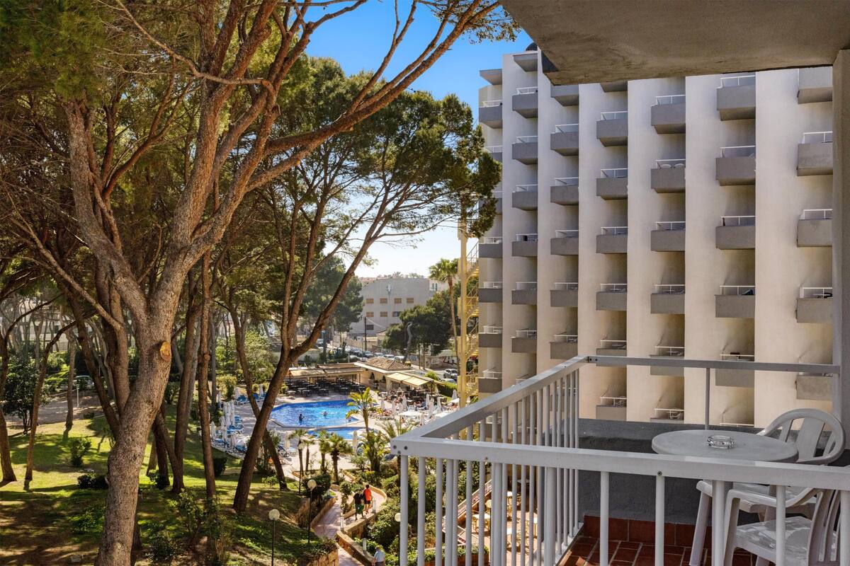 Un balcon donnant sur une piscine, des arbres et un immeuble doté de balcons.