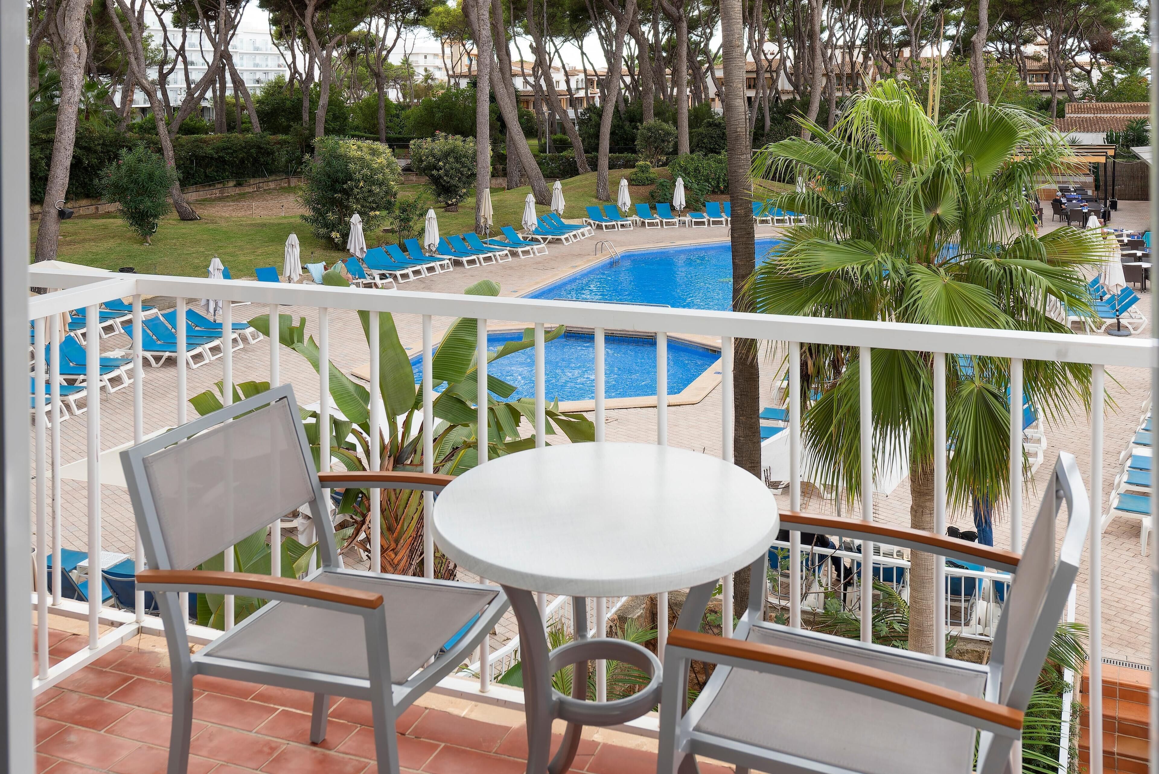 Ein Balkon mit Blick auf einen Pool, Stühlen und einem Tisch.