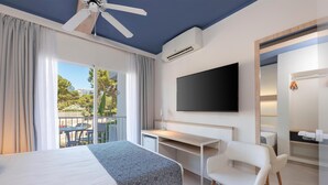 Habitació d'hotel amb llit, escriptori, cadira, televisió i un balcó amb taula i cadires.