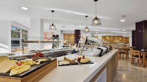 Zona de bufé con varios quesos, frutas y una estación de café.