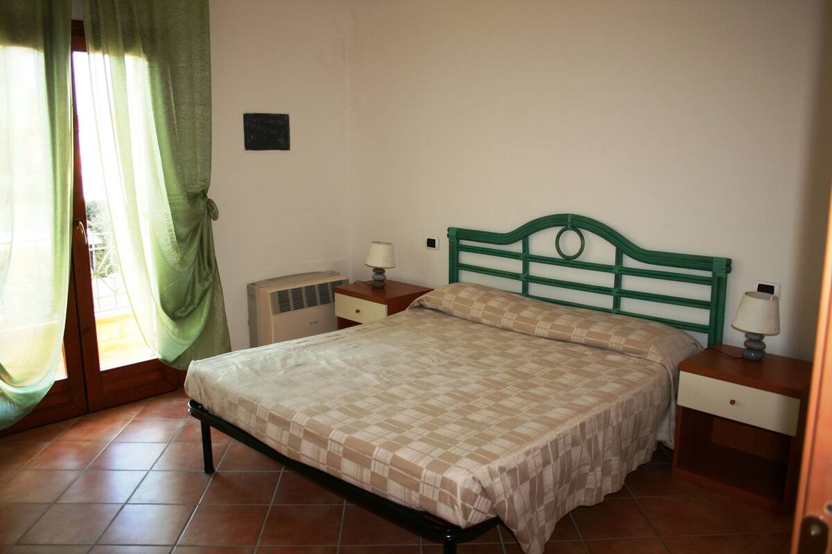 Une chambre à coucher avec un lit, des tables de chevet et une fenêtre avec des rideaux.