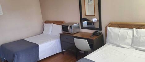 A hotel room with two beds, a desk with a telephone, a microwave, and a mirror.