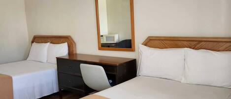 Une chambre d’hôtel avec deux lits, un bureau et un miroir.