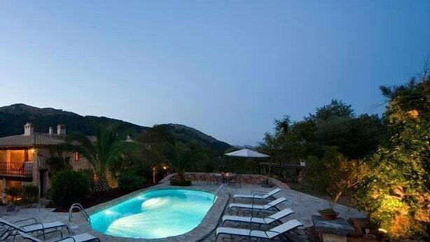 A pool area with lounge chairs and a house in the background. - Vall de Pollença (Pollenca)