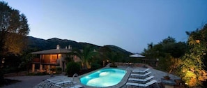 A pool area with lounge chairs and a house in the background. - Vall de Pollença (Pollenca)