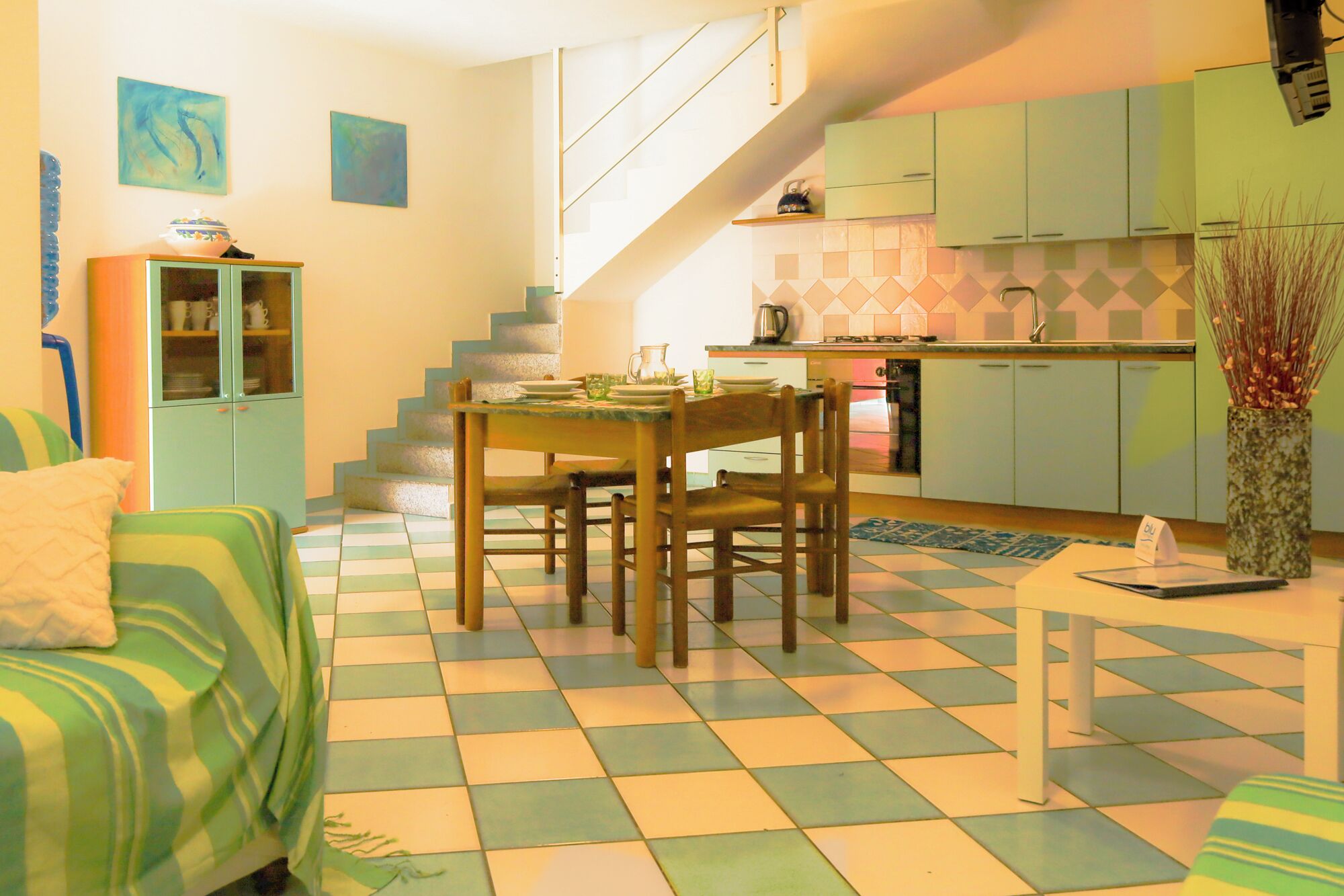 A compact living space with a dining area, kitchen, and staircase.