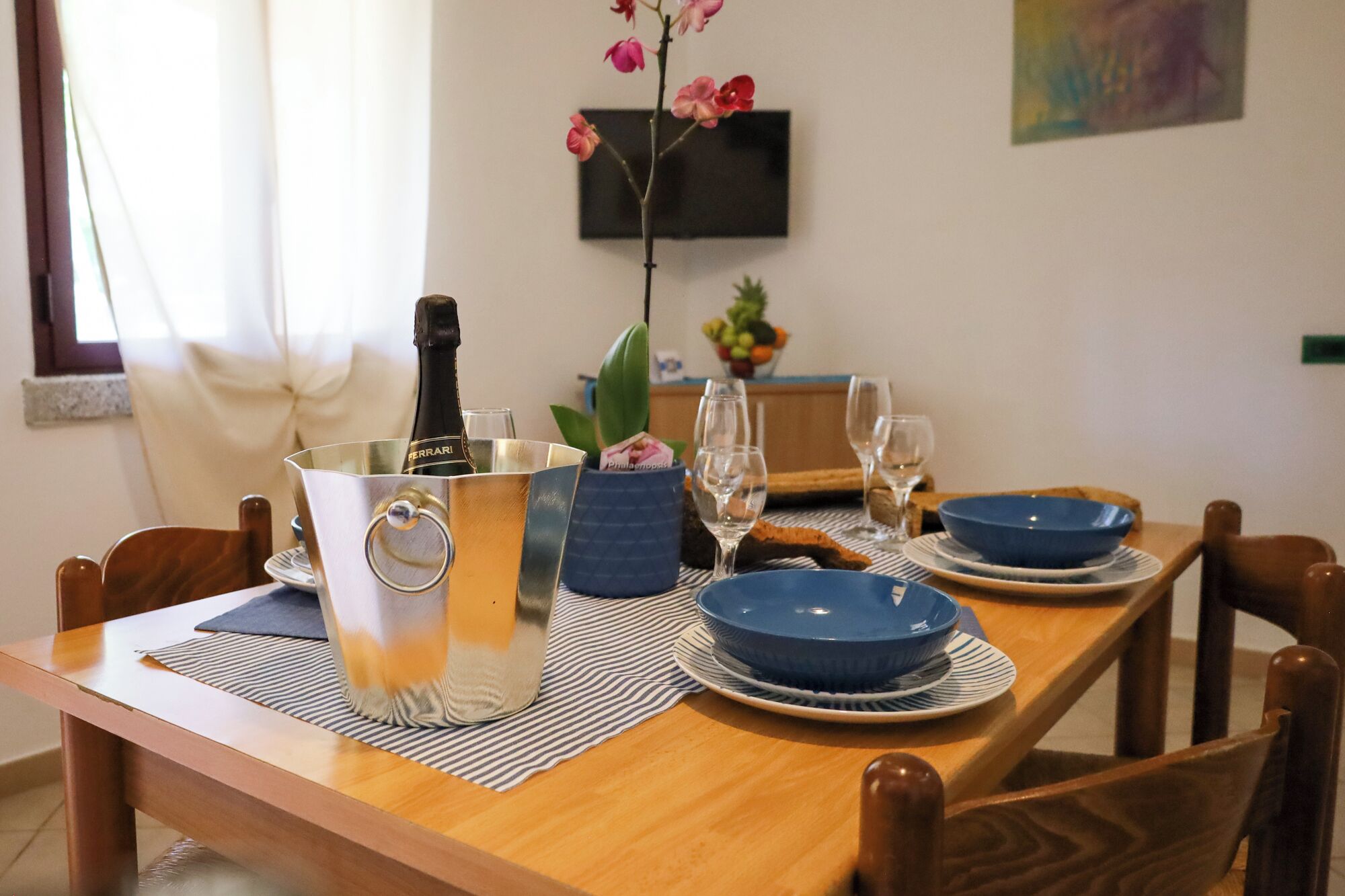 A dining table set with blue plates, a bottle of champagne, and wine glasses.