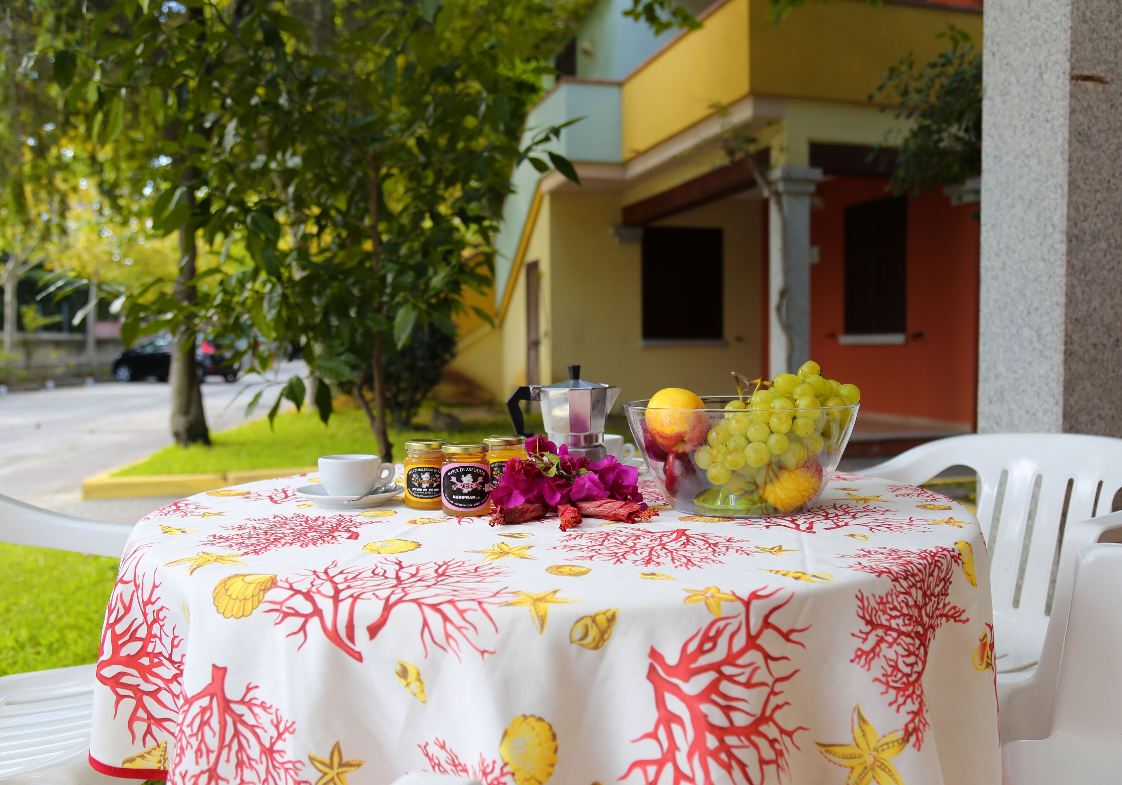 A table set outdoors with a tablecloth, a fruit bowl, a pitcher, and a cup.