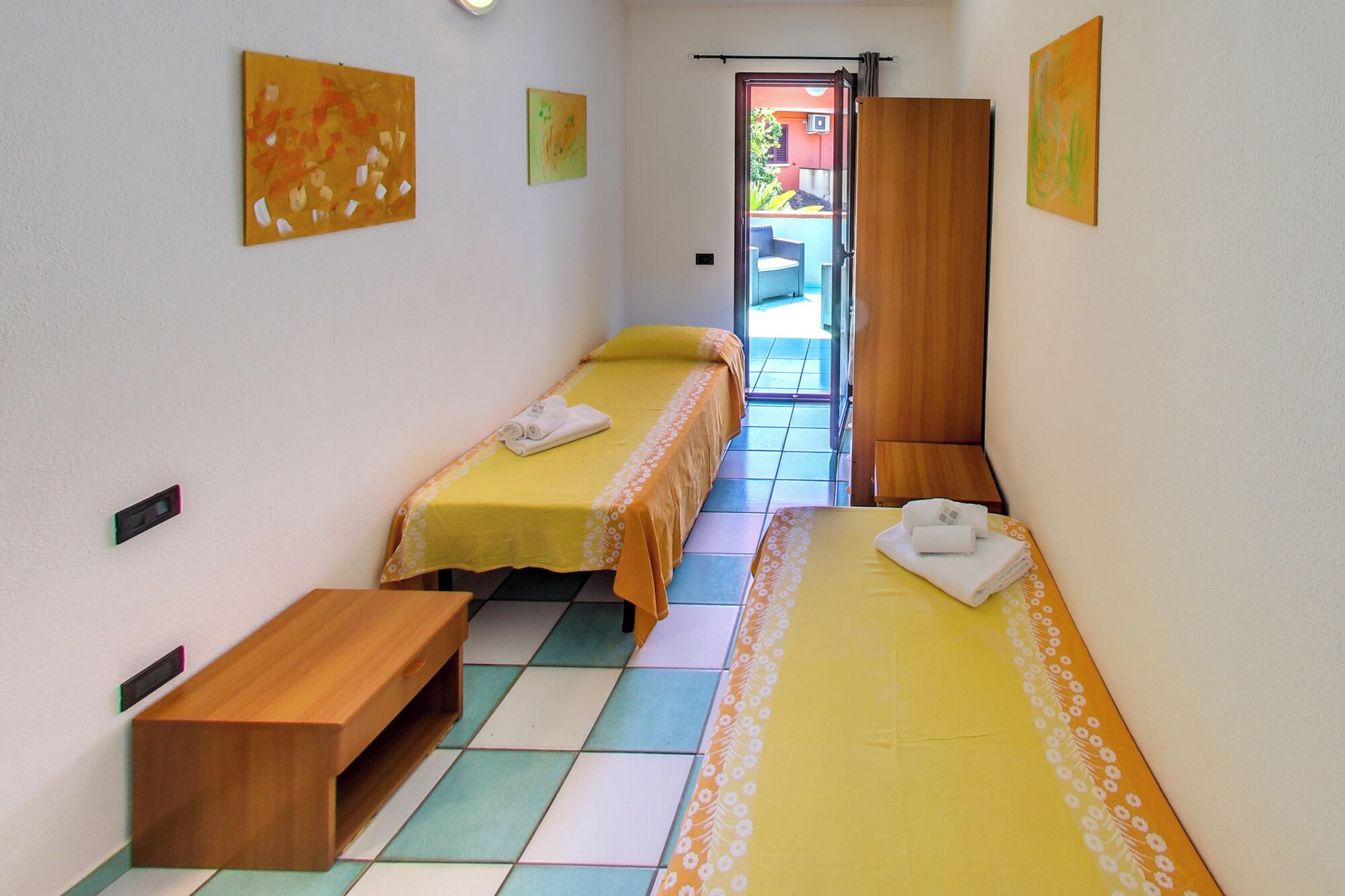 Una habitación con dos camas, un banco de madera y piso de baldosas.