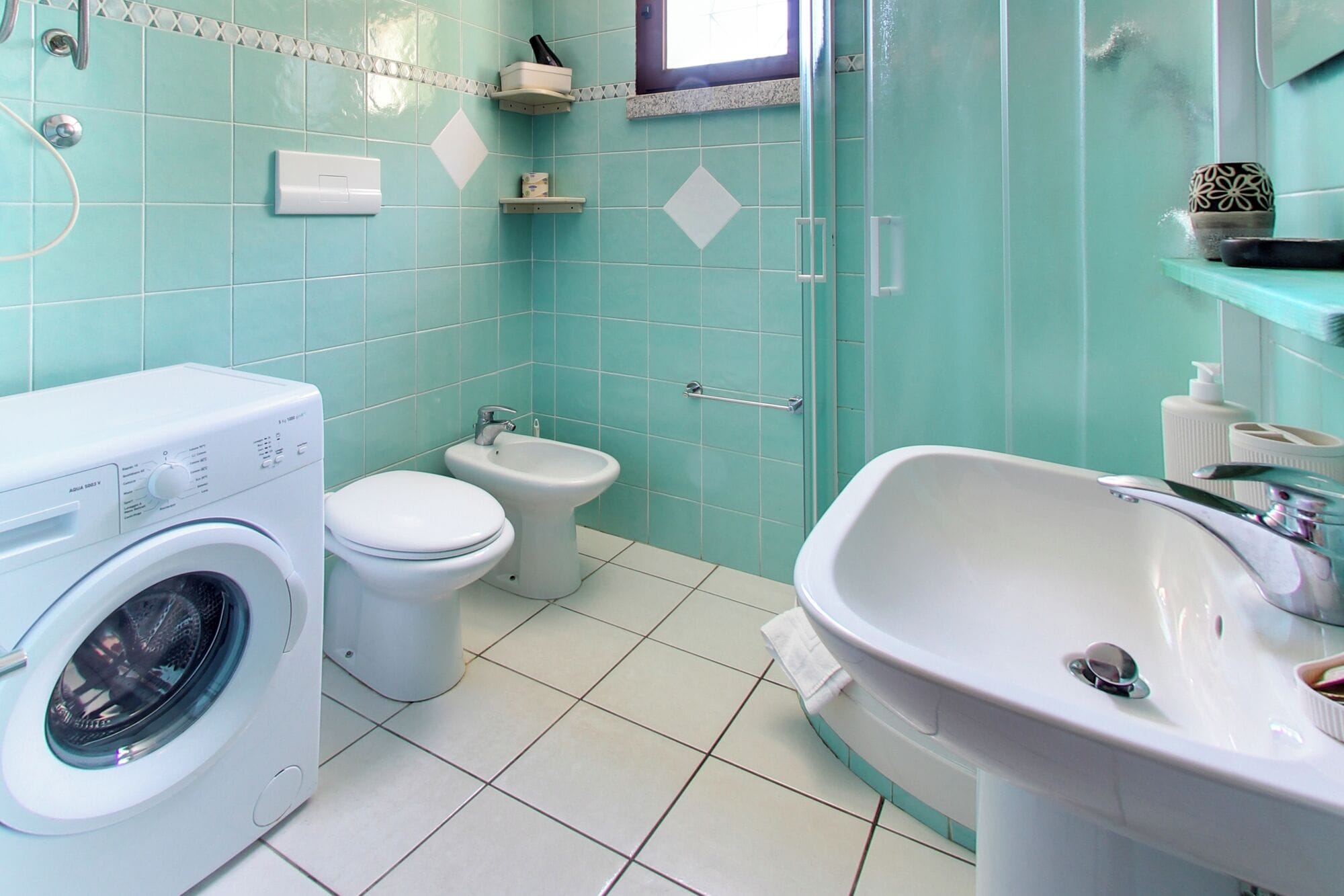 Baño con lavadora, inodoro, bidé y lavamanos.