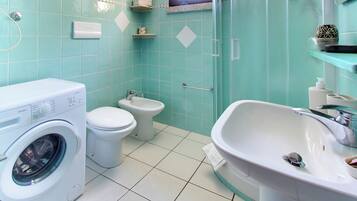 Baño con lavadora, inodoro, bidé y lavamanos.