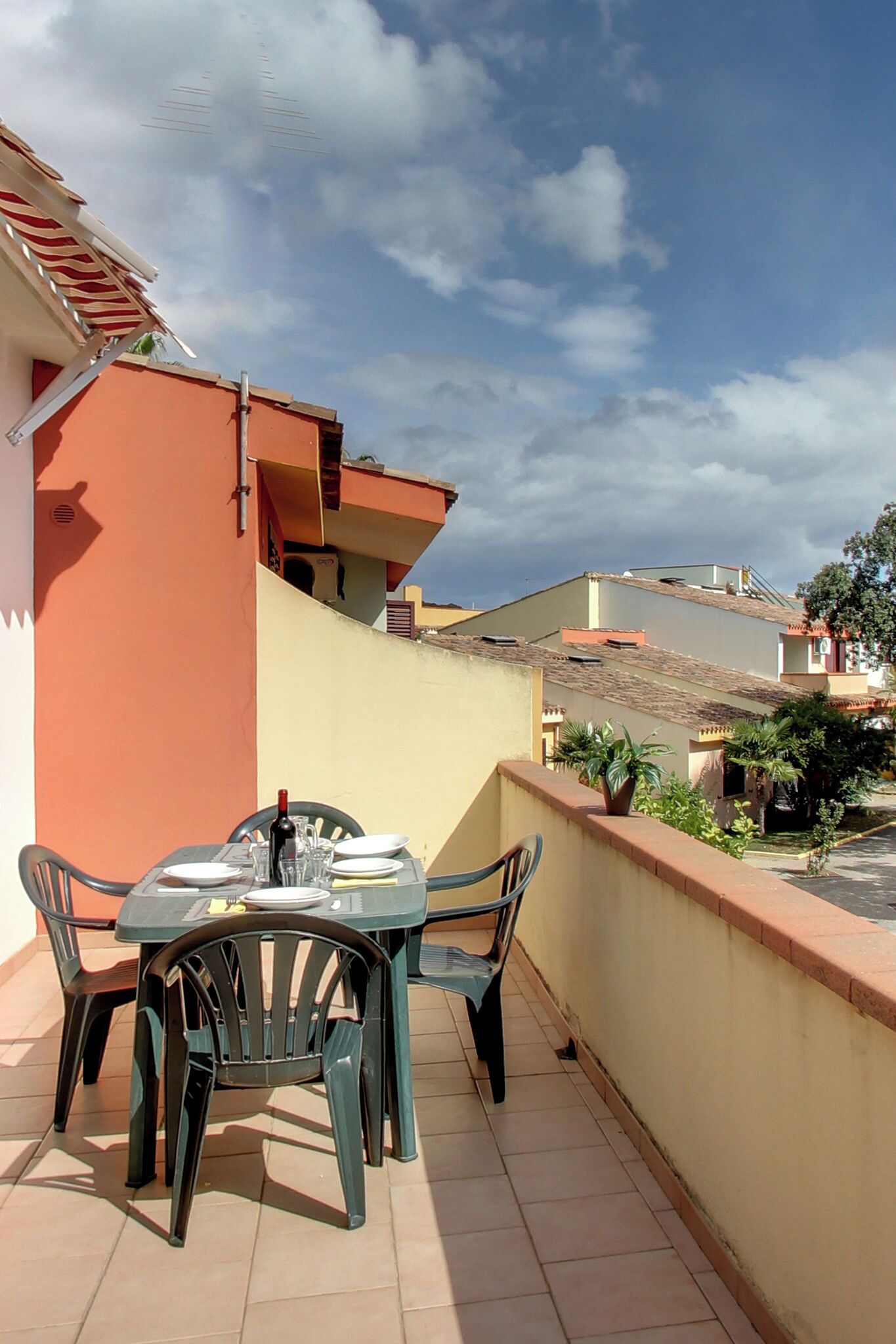 A balcony with a table and chairs, a bottle of wine, and a potted plant.