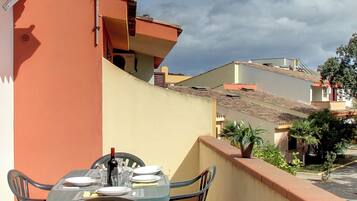 A balcony with a table and chairs, a bottle of wine, and a potted plant.
