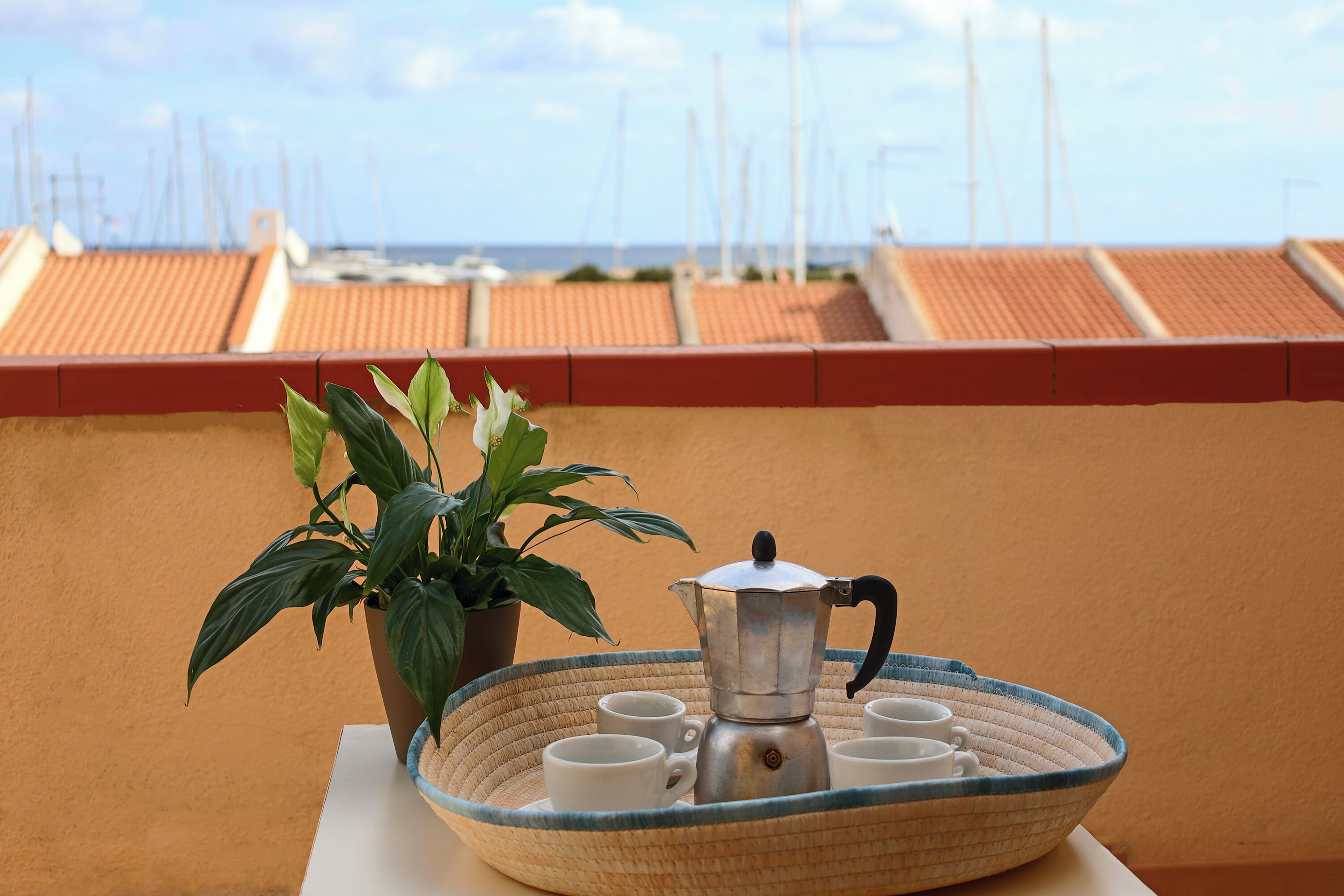 A terrace with a coffee setup, including a metal pot and cups, and a potted plant.
