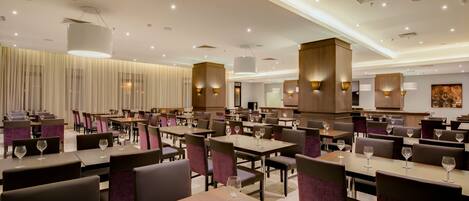 A spacious restaurant with multiple dining tables and chairs, equipped with wine glasses.
