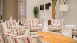 A modern indoor seating area with patterned chairs and a central round table. - Linx Confins by Wish (Confins)