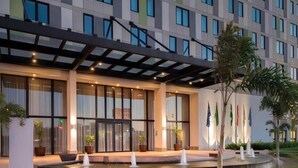 A modern hotel with a covered entrance, large windows, and a well-lit facade. - Linx Confins by Wish (Confins)