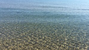 Vista clara de una masa de agua poco profunda con piedras y rocas visibles.