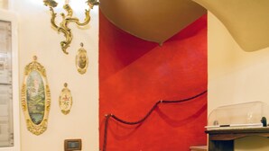 Una escalera con paredes rojas, un candelabro y una barandilla de cuerda roja.
