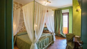 Un dormitorio con cama con dosel, cortinas verdes y pared de piedra.