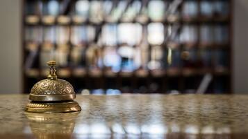 A brass bell on a polished marble surface with a blurred background of shelves and bottles.