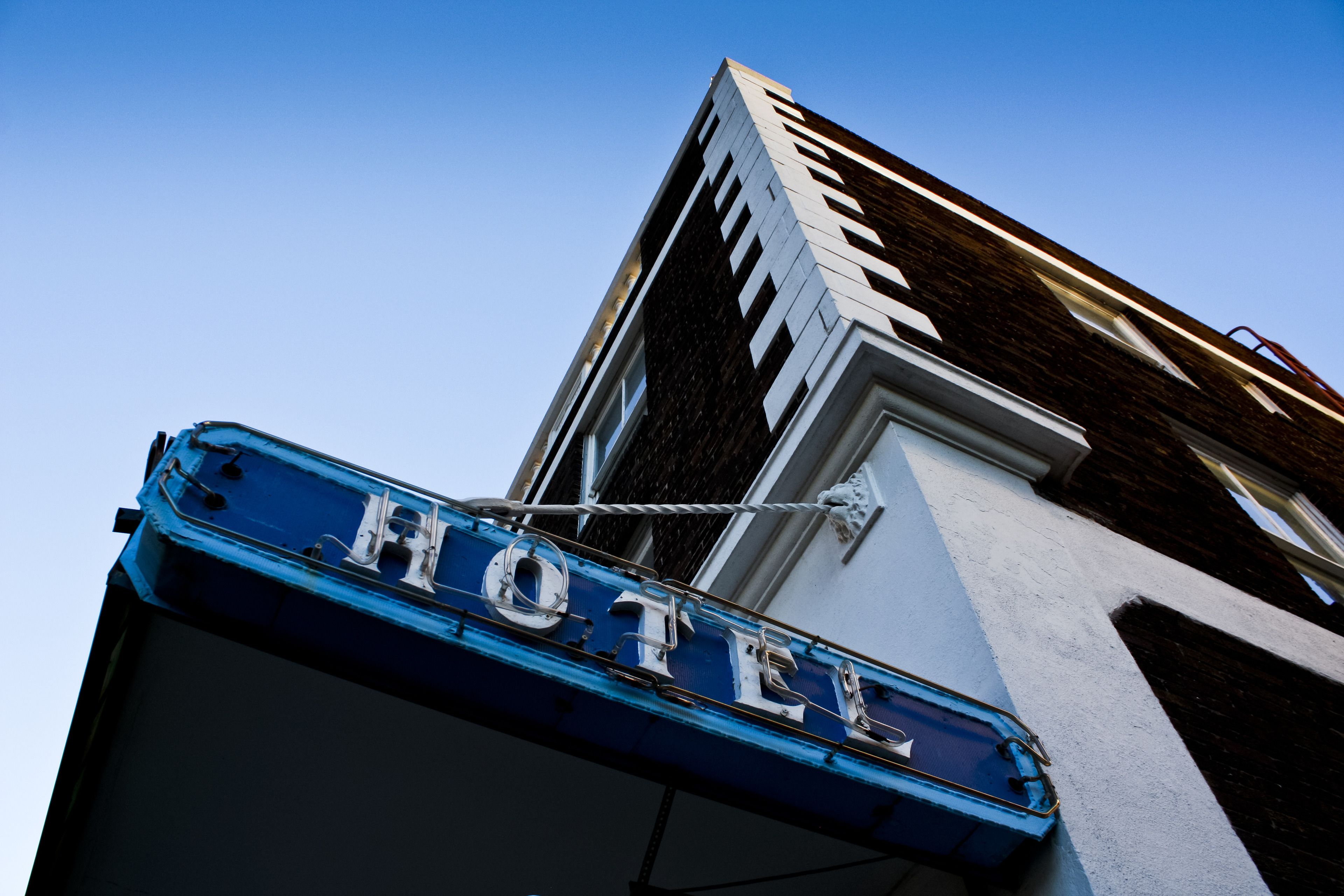 A hotel sign with the word "HOTEL" in large letters, mounted on a building with a clear blue sky in the background.