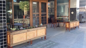 A wooden bench with wheels, a glass door, and a window with a view of the street. - The Gardner  (El Paso)