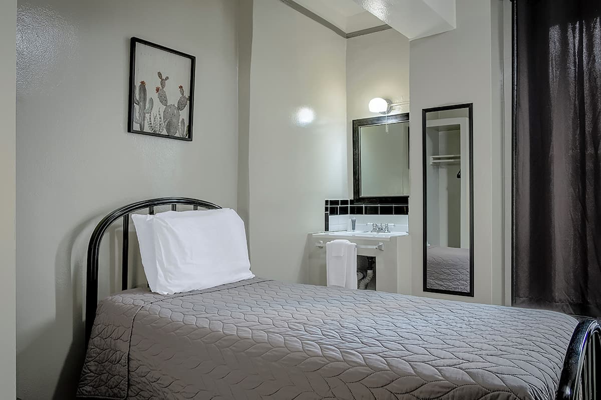 Una habitación de hotel con cama, un baño con espejo y una puerta.